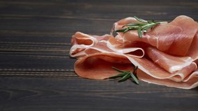 sliced prosciutto or jamon meat on wooden background