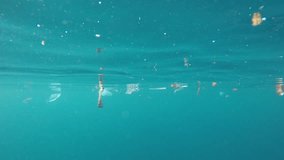Underwater footage of plastic pollution problem in ocean. Plastic bottles, bags and straws, and tin cans are dumped in sea