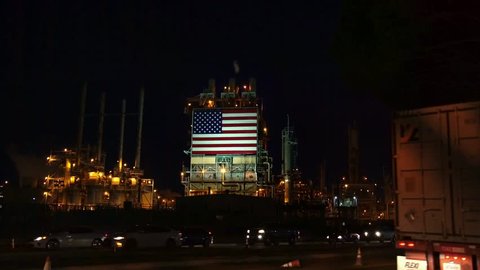 LOS ANGELES, CALIFORNIA, USA - MAY 8, 2018: American flag on Oil Refinery. Smoke fumes coming out of oil refinery Power Plant Fossil Fuel, near Los Angeles, USA. Global Warming and Climate Change
