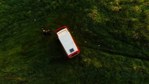 MILSKO, LUBUSKIE, POLAND - APRIL 12, 2018: Classic Orange and white Volkswagen camper van parked in green meadows. Drone footage looking directly down from above and ascending. 