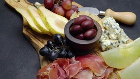 Meat and cheese plate antipasti snack with Prosciutto, melon, grapes and cheese