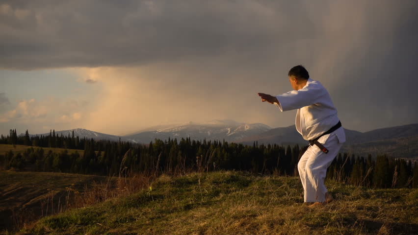 a man engaged in martial arts in the mountains. spring, super slow motion, meditation, white kimono. Asia