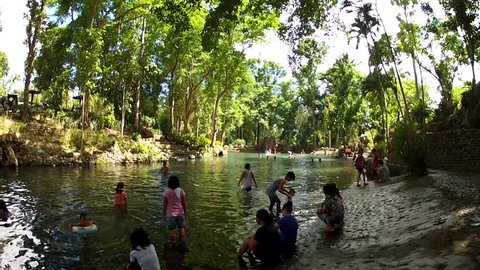 LAGUNA, PHILIPPINES - MAY 22, 2015: people bathe in cold and clear rocky mountain spring river water on hot summer tracking shot