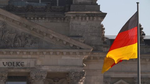 German national flag in front of the Reichstag building in Berlin.