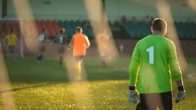 Goalkeeper walks in slow motion, rear view, team playing match, amateur championship, digit 1 on goalee's T-shirt - Powered by Shutterstock - Get 15% off with code: PIKWIZARD15