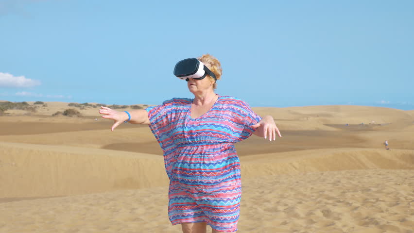 Professional video of senior woman wearing virtual googles on desert in 4k slow motion  - Powered by Shutterstock - Get 15% off with code: PIKWIZARD15