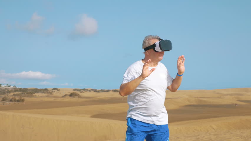 Professional video of senior man  wearing virtual googles on desert in 4k slow motion  - Powered by Shutterstock - Get 15% off with code: PIKWIZARD15