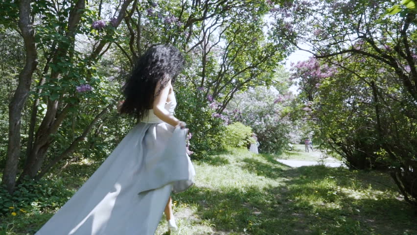 Young laughing woman with red apple running through sunny garden, slow motion