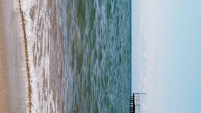Vertical video. Waters of the lake Issyk-Kul in the background of mountains, beach town of Cholpon Ata. Issyk Kul, Kyrgyzstan