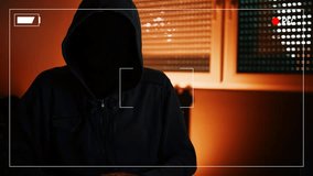 Hacker ransomware demands, computer crime and network security concept. Hooded male person recorded spoken list of requests to be paid as ransom for unlocking access to computer.