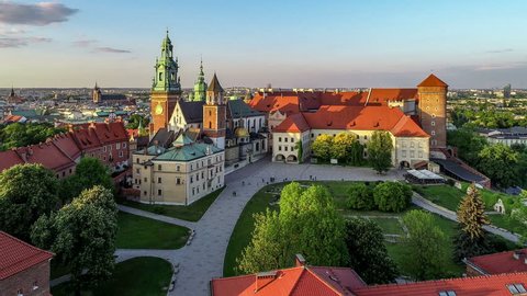 Royal Wawel Gothic Cathedral in Cracow, Poland, with Wawel castle, yard, park, tourists and Vistula river. Aerial 4K reveal video at sunset in spring. Old city with St. Mary church in the background