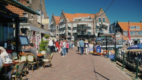 Volendam, Netherlands, May 2018: Walking along the street of fishing village Volendam. Many tourists, souvenir shops and cafes