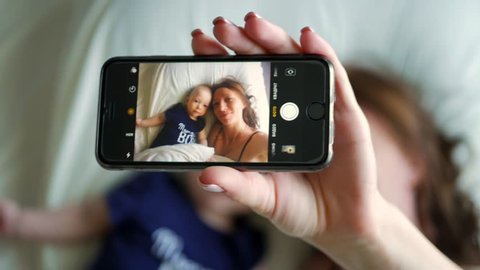 Mother and small baby boy doing selfie on bed. Resting in bed together. Maternity concept. Parenthood. Motherhood Beautiful Happy Family Stock Video Footage.