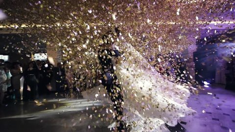 First dance of wedding pair in flying gold confetti. 
