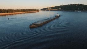 Barge sails along the river near the city port on sunset aerial footage