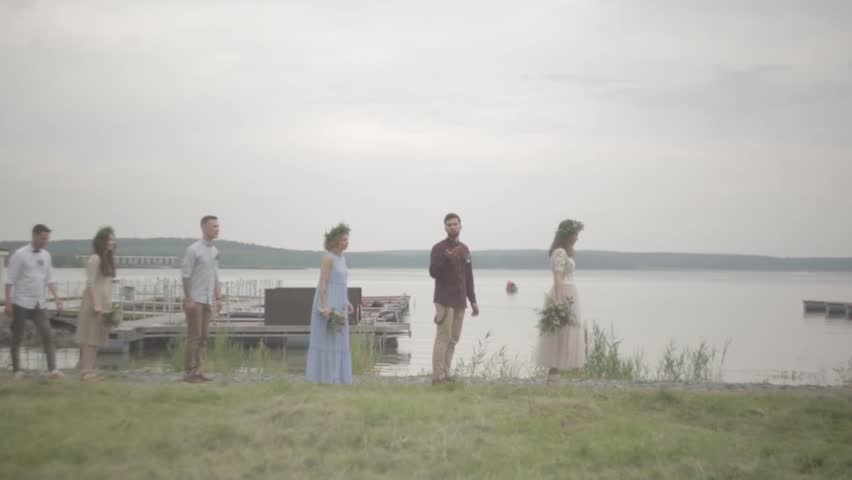 Newlyweds guests walking laughing amid lake