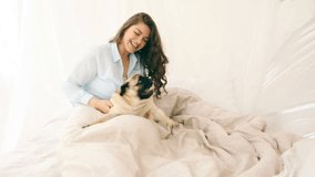 attractive brunette woman playing in bed with her pug dog. LOvely family weekend mornings video footage