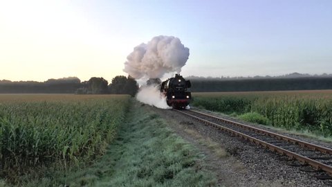 An old steam train with a nice smoke plum in the Netherlands in the morning. The steam locomotive is pulling a freight train.