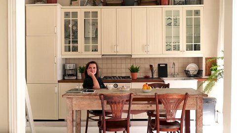 Young, happy woman drinking and relaxing in the kitchen,
