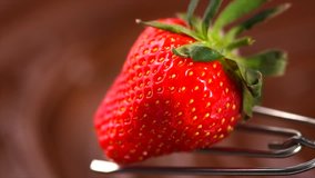 Strawberry in chocolate over swirl brown background. Melted Chocolate pouring on fresh ripe juicy strawberry close up. Dessert. Gourmet food. Fondue. 4K UHD slow motion video