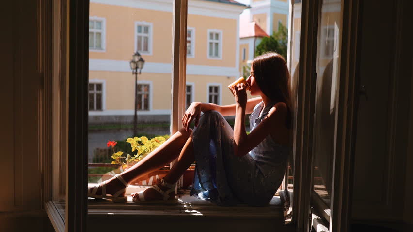 Young girl sitting on window and dreaming.