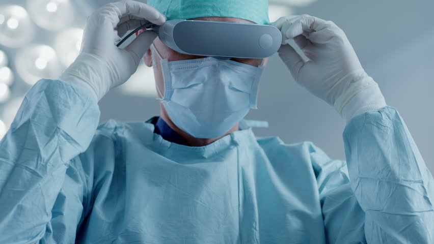 In the Hospital Operating Room Professional Surgeon Puts on Virtual Reality Glasses. Shot on RED EPIC-W 8K Helium Cinema Camera. - Powered by Shutterstock - Get 15% off with code: PIKWIZARD15