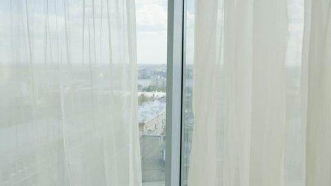 Medium shot of beautiful blonde woman in red lingerie and white shirt taking photos of city view from the panoramic window of the hotel room. 4K