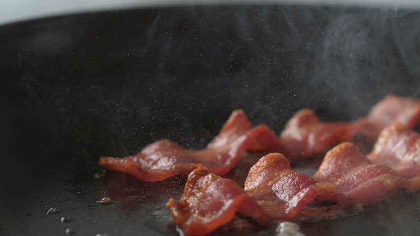 Camera follows cooking bacon on grill. Shot with high speed camera, phantom flex 4K. Slow Motion. Royalty-Free Stock Footage #1011040544