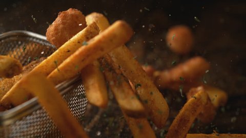Camera follows french fries falling on wooden table. Shot with high speed camera, phantom flex 4K. Slow Motion.