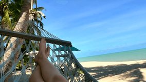video of girl's feet swinging on a hammock at the beach