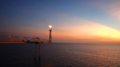 footage of oil and gas platform with flare burning bridge with sun rise and beautiful clouds in the morning for oil and gas industry concept.