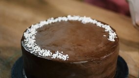 Decorating chocolate coconut cake with coconut shavings.