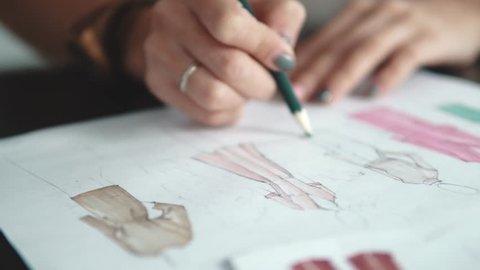 designer of clothes makes an outline of clothes with a felt-tip pen. female hands closeup