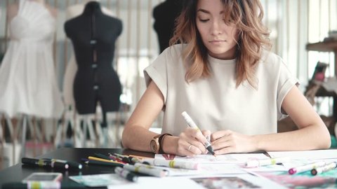 ashion designer makes a sketch on paper and sends a message from a mobile phone. business woman working in her atelier – Video có sẵn