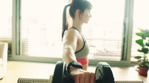Young fitness woman doing exercise with dumbbells at home.