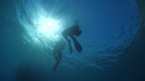 scuba divers ascending surface underwater sun rays and beams