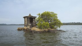 Tiny island with a religious shrine and sparse growth of young mangrove trees. in a river delta near Hikkaduwa. Sri Lanka. Ultra HD 4k video