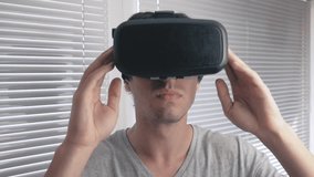 Young man using his VR headset for watching the 360 video at office background. Close up.