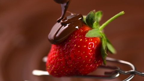 Strawberry in chocolate over swirl brown background. Melted Chocolate pouring on fresh ripe juicy strawberry close up. Dessert. Gourmet food. Fondue. 4K UHD video