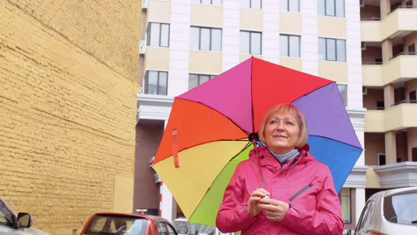 Senior woman with colorful umbrella at building background
