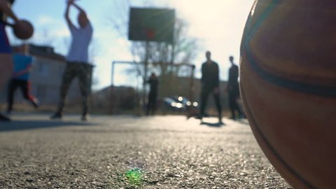 Teenagers on a playground covered with asphalt play basketball.