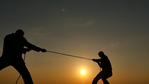 competition concept - tug of war - 2 persons pulls rope silhouettes