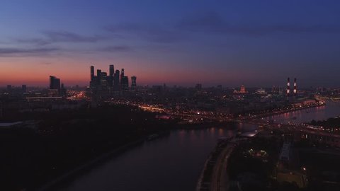 Moscow International Business Center, Moscow-city. Night aerial shot of skyscrapers with city lights and cars on roads and the Moscow river on the background. Aerial high altitude drone flight. UHD 4K