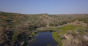 4K high quality aerial summer video of African savanna, small water dam surrounded by bushy hills in Daan Viljoen National Reserve in Khomas Hochland area near Windhoek, Namibia's capital, Africa