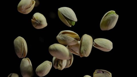 Pistachios bouncing against to the camera on a black background in slow motion closeup,