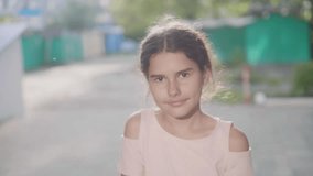 Little girl in an urban setting smiles at lifestyle the camera slow motion video