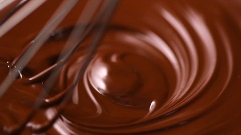 Chocolate. Mixing melted liquid premium dark chocolate with a whisk. Close up of liquid hot chocolate swirl. Confectionery. Confectioner prepares dessert, icing. 4K UHD video, slow motion 120 fps