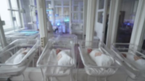 Blurred view of interior maternity hospital, newborn babies in cots.
