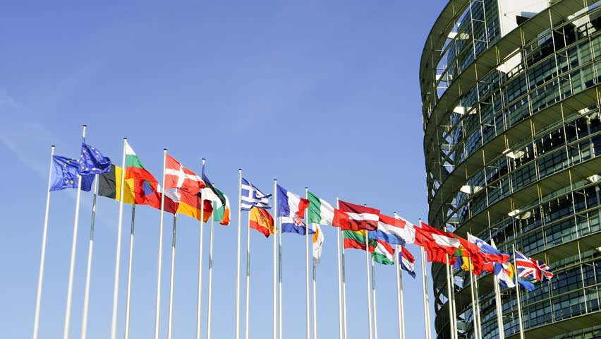 Side view of EU members flags waving in front of European Parliament building in Strasbourg, France early in the morning - slow motion cinematic and clear blue sky Royalty-Free Stock Footage #1011130847