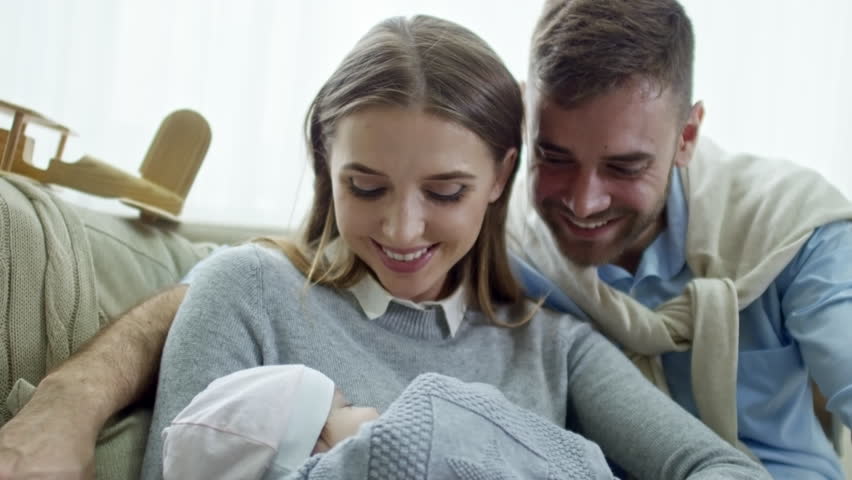 Tilt up of happy young woman and man looking at sleeping baby and smiling | Shutterstock HD Video #1011134261